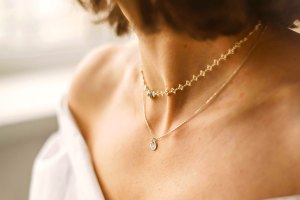 A woman's neck with two gold necklaces.