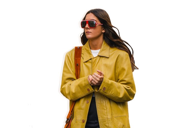 brunette woman wearing yellow jacket with red bag and sunglasses