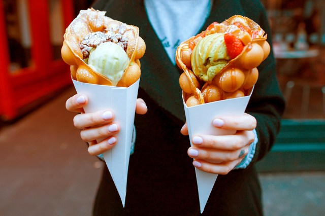 two hands with white nails holding ice cream dessert cones