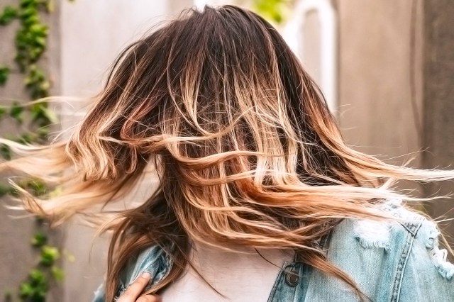 woman against the wall with blonde hair and brown roots