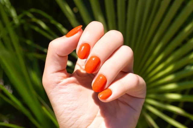 white hand with orange nails