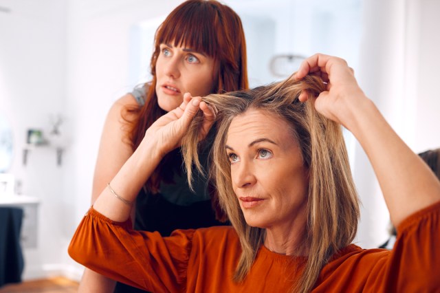 woman in a hair salon chair and hairstylist behind her