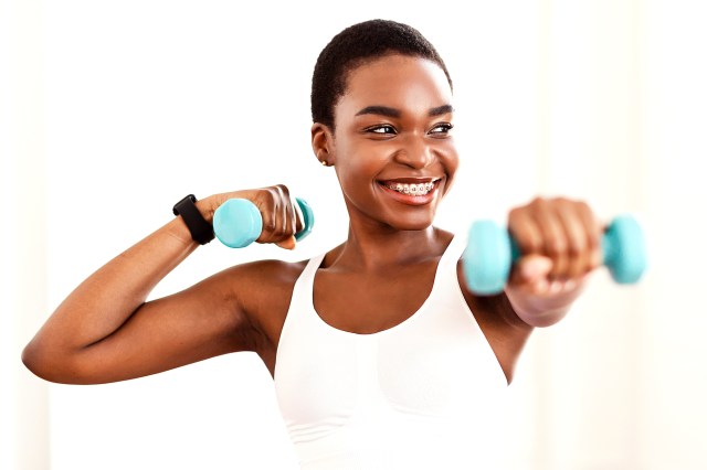 black woman with blue weights smiling 