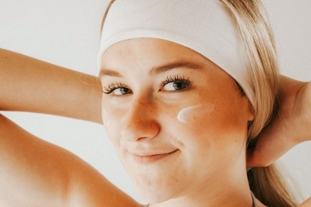 girl wearing white headband with skincare on her face