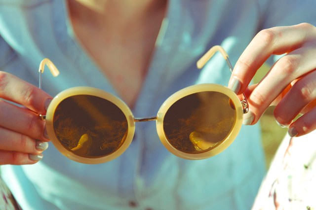 hands holding yellow sunglasses