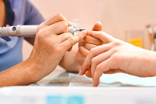 a woman using a nail drill on a hand/nails 