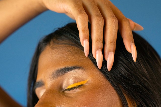 woman with yellow eyeliner and long pink nails 
