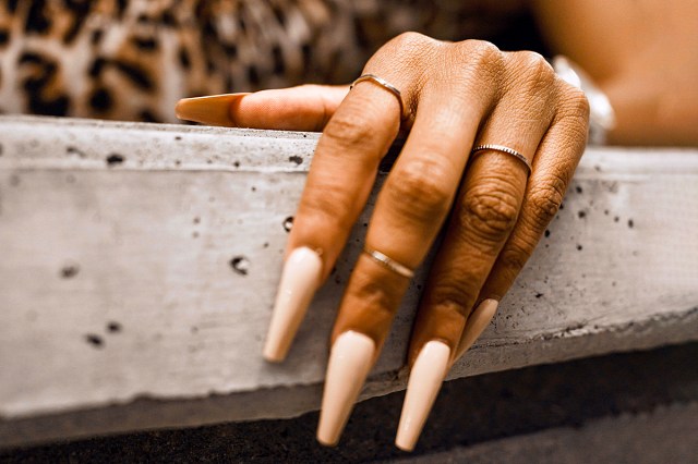 black hand with long tan nails and silver rings 
