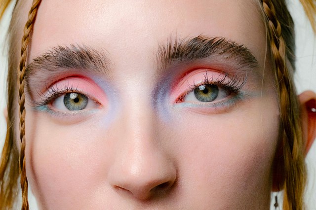 a close up of a woman's face with pink and blue makeup