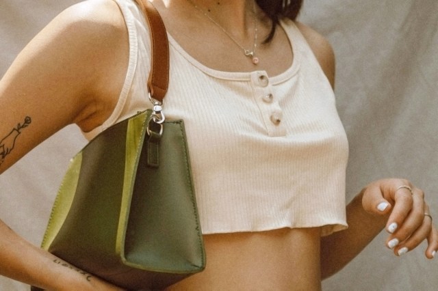woman in white crop top with green purse