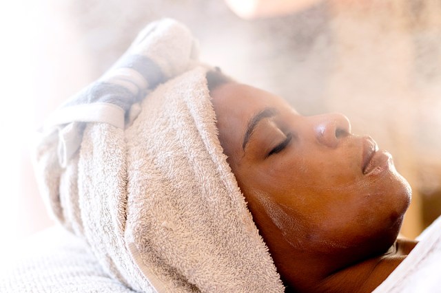 Adult African woman relaxing & enjoying a facial treatment at a beauty salon.