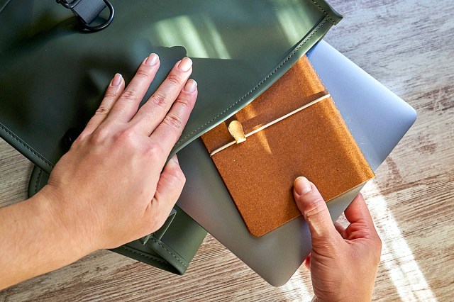 Hands of a woman prepare her office supplies in a backpack