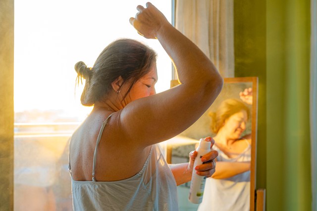 Woman applying deodorant on underarm