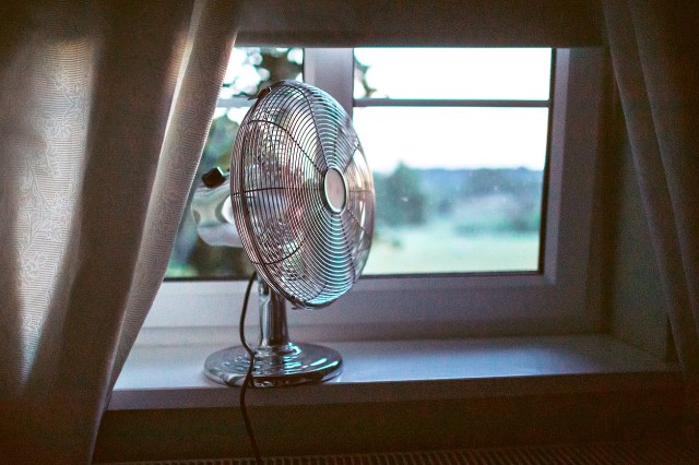 Cooling fan in the light hot summer night by the open window