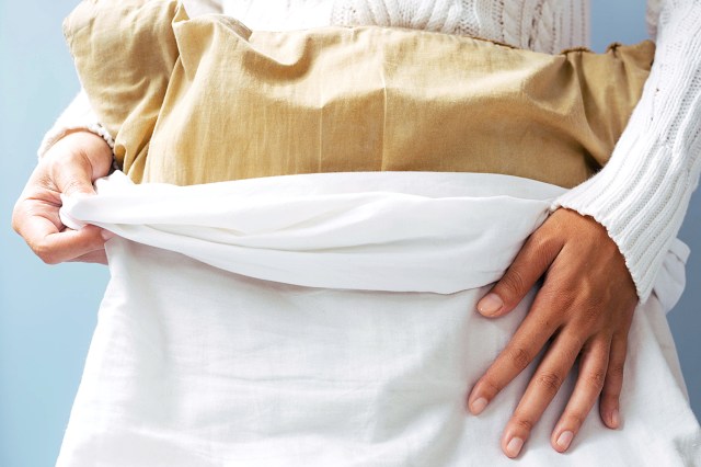 woman putting pillowcase on a pillow 