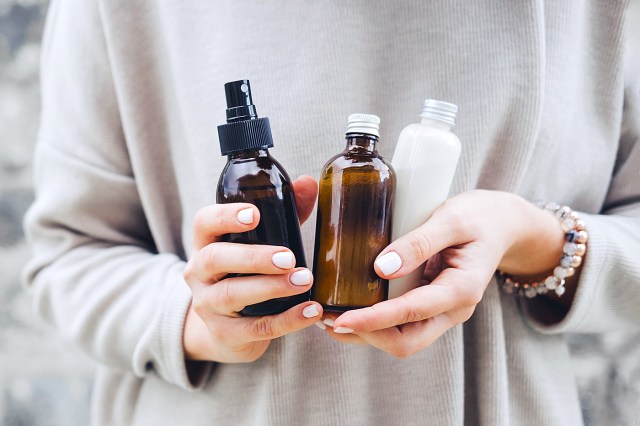 Woman holding three various bottles of skin care products