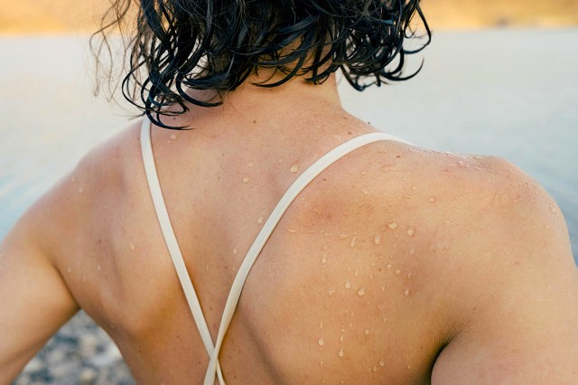 a person with wet hair standing by a body of water