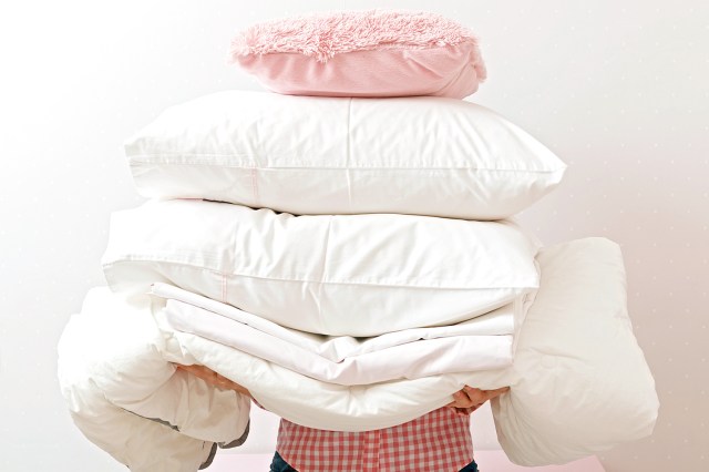 Woman holding a pile of bedding for sleeping.