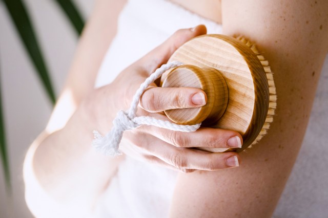 Woman holding round wooden brush for dry body massage