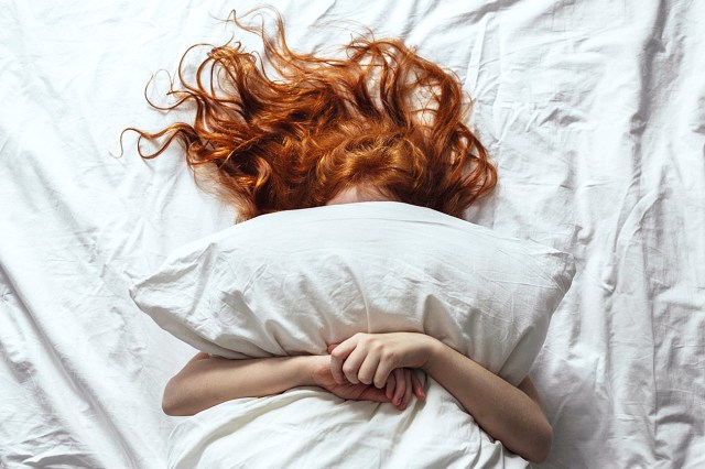 Red-haired girl under a pillow