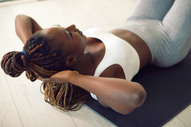 Young black sportswoman doing sit-ups while exercising in the living room.
