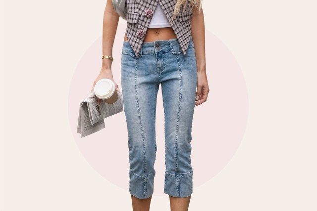 Emili Sindlev wears glasses, a white crop t-shirt, a checkered / checked pattern printed waistcoat with bejeweled / rhinestones buttons, cropped blue denim jeans pants , pointed shoes, holds newspaper and a coffee cup