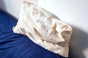Old used white pillow with yellow stains. Dirty pillow on the bed.
