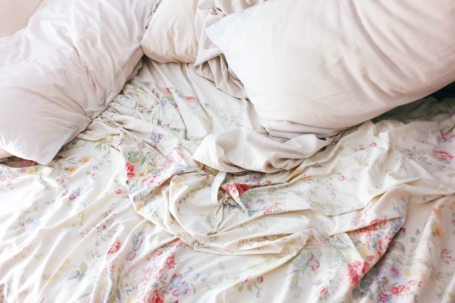 Unmade bed with flower sheets and pillows