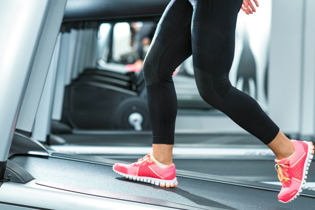 Cropped image of person walking on treadmill, black leggings and pink shoes