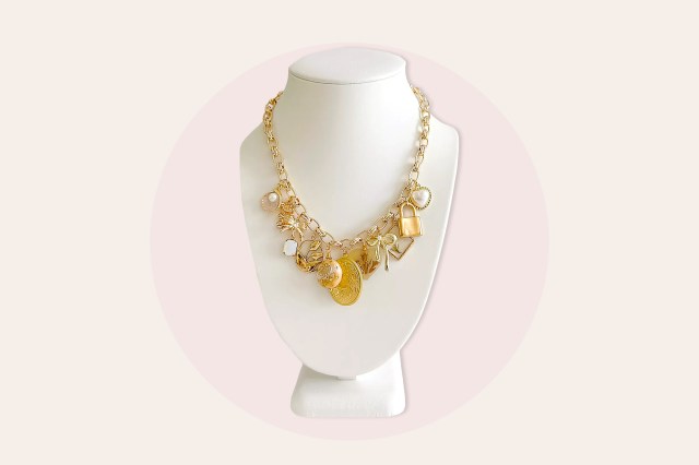 Gold charm necklace with many charms on a white neck model