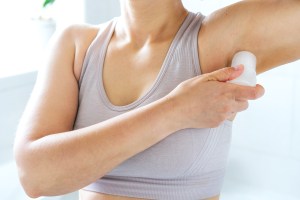 Woman putting deodorant on her arm pits