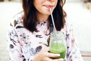 Woman drinking green smoothie with metal straw