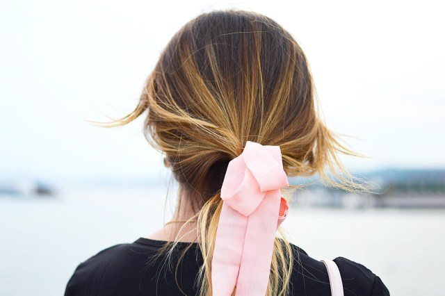 Rear view image of woman with pink, ribbon tying her hair back