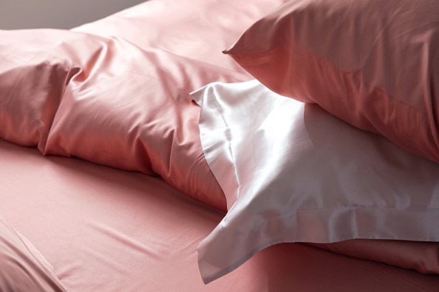 Close up of silk pillows on a bed, pink sheets