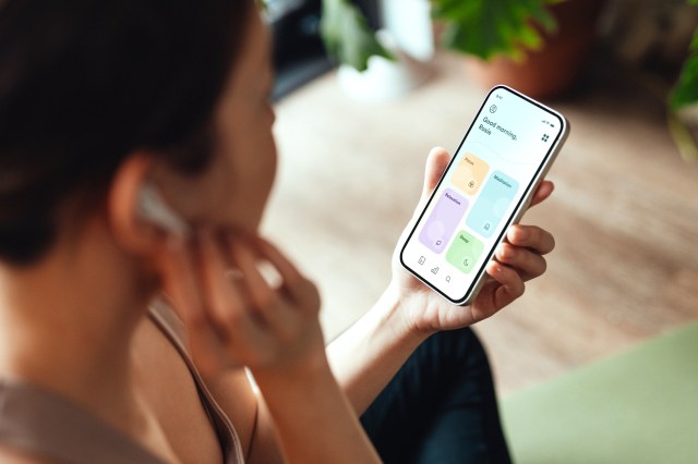 Close-up of person using mindfulness app on their smartphone, wearing AirPods