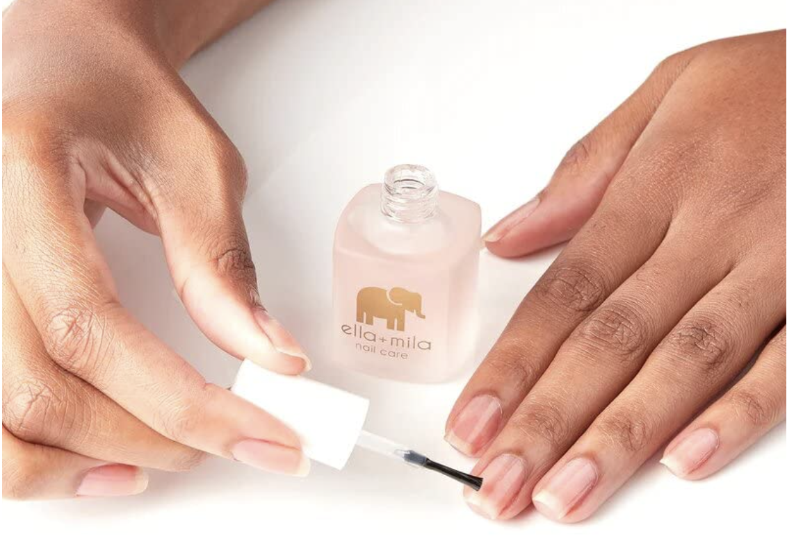 Hand putting on nail strengthener polish onto nails with an ella+mila nail care bottle