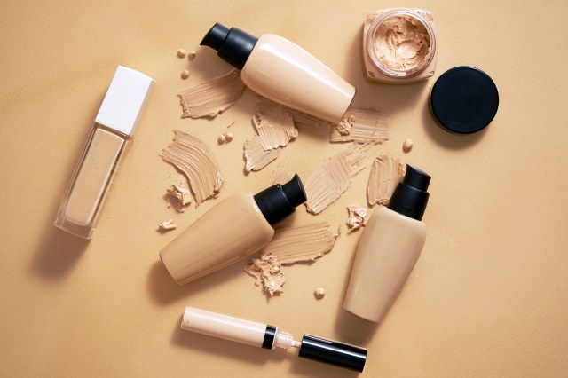 Foundation/concealer bottles/products and smudges on a neutral background