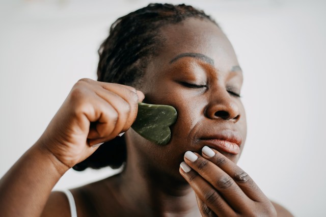 Woman using gua sha tool on her face