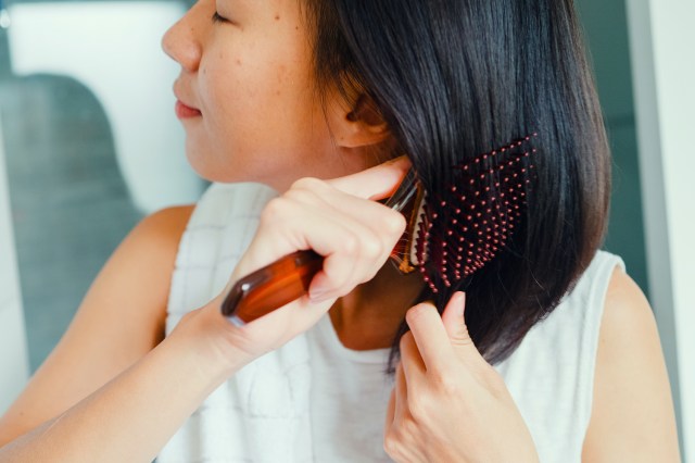 Closeup of young woman combing her hair