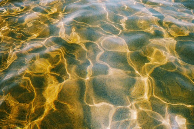 Close up of clear, rippling water, view of sand on the ground