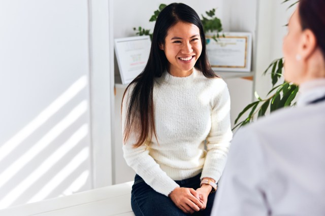 Smiling woman talking to doctor in office