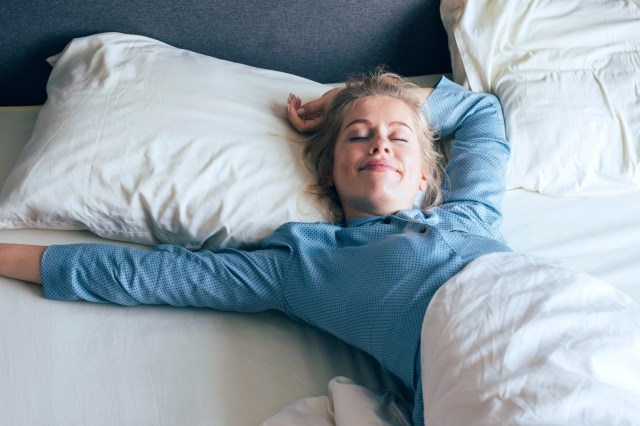 Young woman stretching her arms in bed on a sunny morning