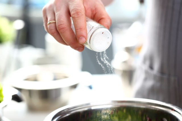 Close up of person salting food while cooking