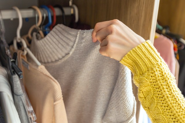 Person choosing sweater from closet