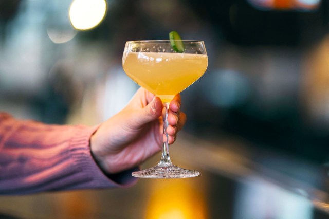 Close up of hand holding yellow cocktail