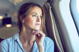 Serious woman looking out of airplane window