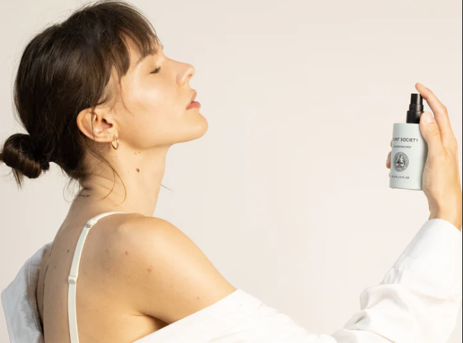 Woman spraying Fount Society face mist onto face