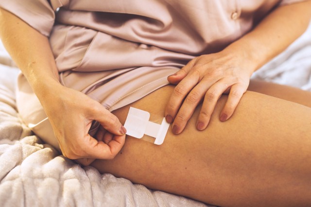 Woman sitting on bed doing HRT (hormone replacement therapy) treatment