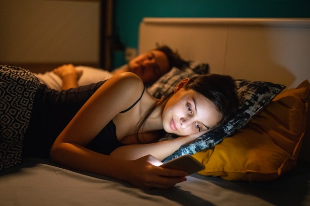 Young woman in bed with her mobile phone