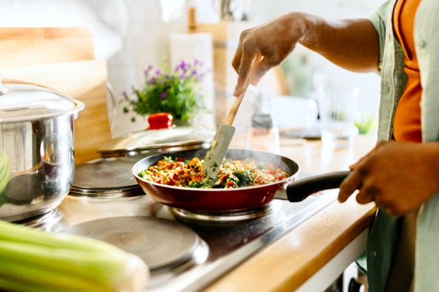 Woman preparing quinoa vegetable mix cooked in a frying pan